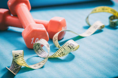 Dumbbells and measure tape on a green yoga matの写真素材
