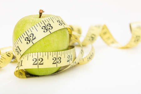 Green apple and measuring tape on white backgroundの写真素材