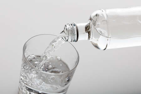 Glass and bottle of water on white background