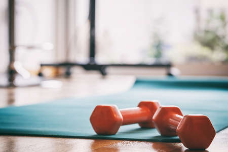 Pair of orange dumbbells on a wooden floorの写真素材