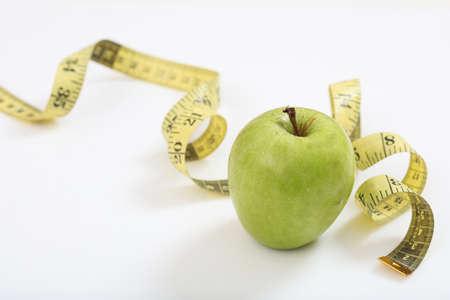 Green apple and measuring tape on white backgroundの写真素材