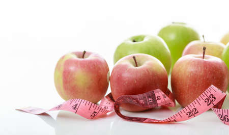 Variety of apples and measure tape on white backgroundの写真素材
