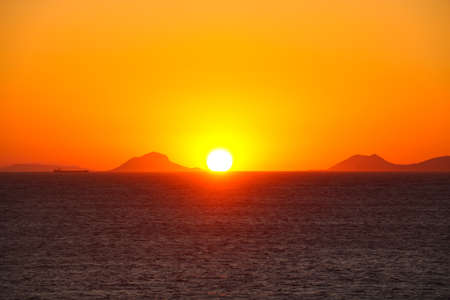 Beautiful sunset over sea water and mountains silhouettesの写真素材