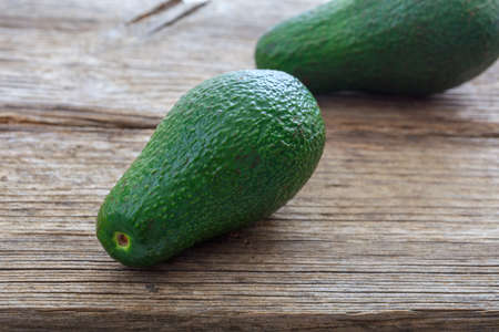 Two whole avocados on a wooden background