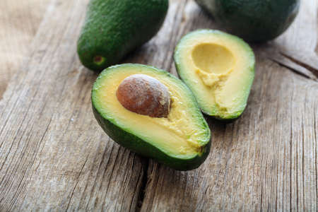 Ávocados cut and whole on a wooden background