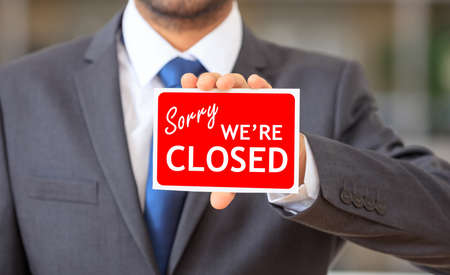 Man holding a red sorry we are closed signの写真素材