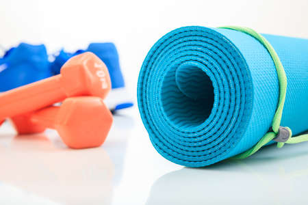 Yoga mat and dumbbells on white background
