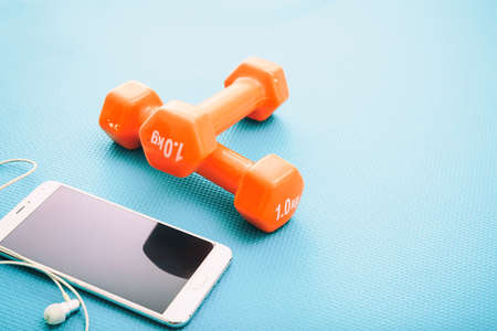 Dumbbells and smartphone on a green yoga matの写真素材