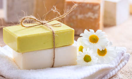 Natural handmade soap bars and chamomile on wooden background