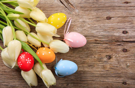 Easter eggs and tulips on wooden background with copy spaceの写真素材