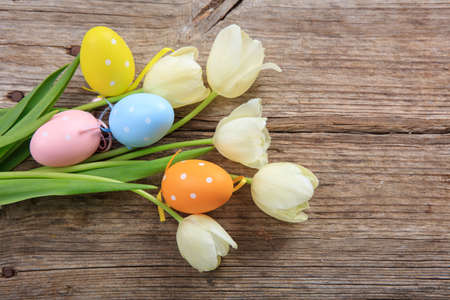 Easter eggs and tulips on wooden background with copy spaceの写真素材