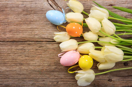 Easter eggs and tulips on wooden background with copy spaceの写真素材