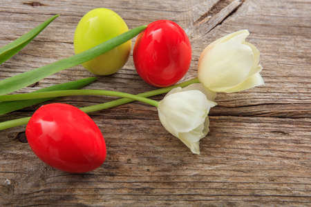 Easter eggs and tulips on a wooden tableの写真素材