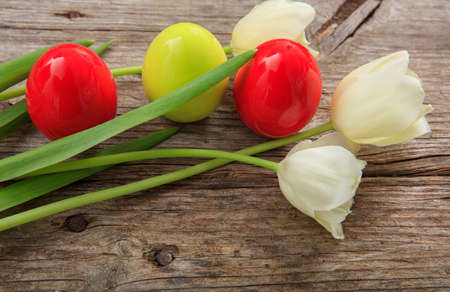 Easter eggs and tulips on a wooden tableの写真素材