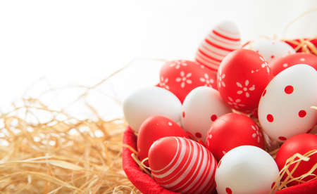 Colorful Easter eggs in a basket on straw backgroundの写真素材