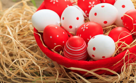 Colorful Easter eggs in a basket on straw backgroundの写真素材