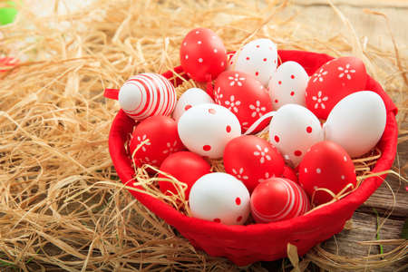 Colorful Easter eggs in a basket on straw backgroundの写真素材