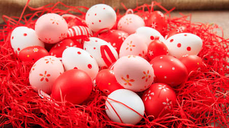 Colorful Easter eggs in a basket on straw backgroundの写真素材