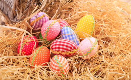 Colorful pastel Easter eggs on straw background
