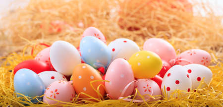 Colorful pastel Easter eggs on straw backgroundの写真素材