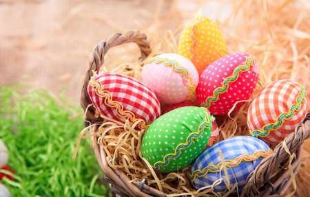 Colorful Easter eggs in a basket on straw backgroundの写真素材