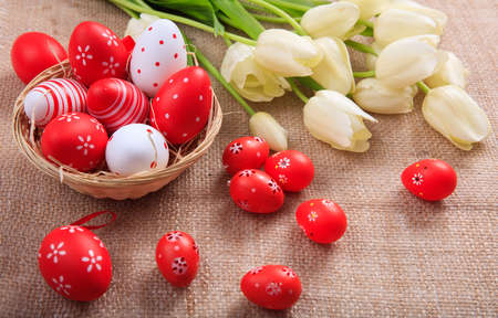 Colorful Easter eggs and white tulips on a burlapの写真素材