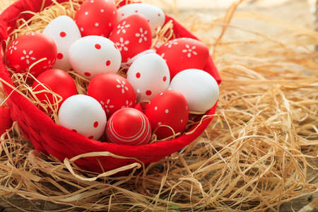 Colorful Easter eggs in a basket on straw backgroundの写真素材
