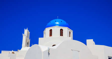 Santorini, Greece - White church with blue dome on blue sky backgroundの写真素材