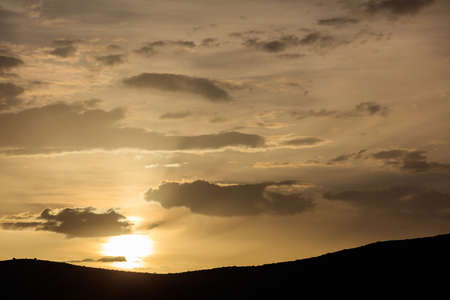Sunrise on a bit cloudy sky over mountains silhouetteの写真素材