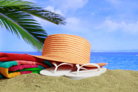 Summer vacations concept - Flip flops and hat on a sandy beachの写真素材