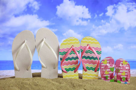 Summer vacations concept - Family flip-flops on a sandy beachの写真素材