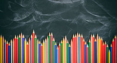 Colored wooden pencils on a black chalkboardの写真素材