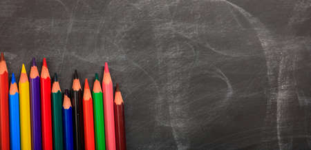 Colored pencils on a black chalkboard - space for captionの写真素材