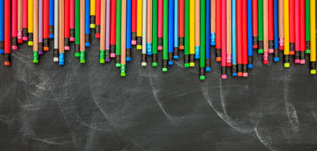 Colored pencils with erasers on a black chalkboardの写真素材