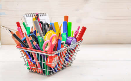 School supplies in a shopping basket on white backgroundの写真素材