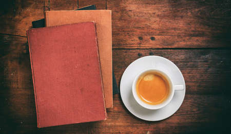 Old books and a cup of coffee on wooden backgroundの写真素材