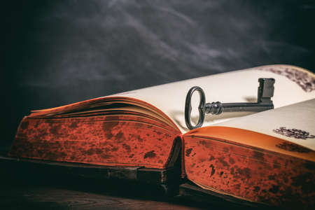 Key to knowledge concept. Key on a vintage book on wooden backgroundの写真素材