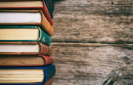 Old books stacked on wooden background - copy spaceの写真素材
