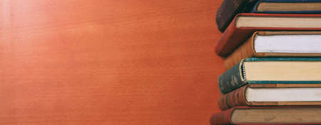 Old books stacked on wooden background - copy space