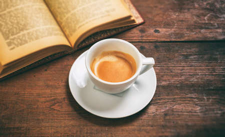 Old book and a cup of coffee on wooden backgroundの写真素材