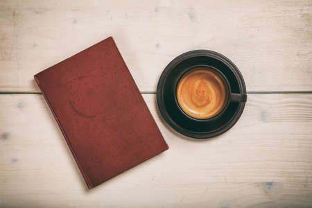 Old book and a cup of coffee on wooden backgroundの写真素材