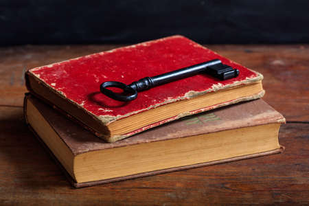 Old books and a key on a wooden tableの写真素材