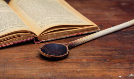 Cookbook concept. Wooden ladle and a vintage bookの写真素材