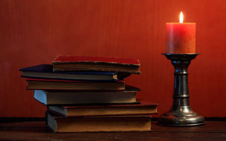 Vintage books stack and candle on blackboard backgroundの写真素材