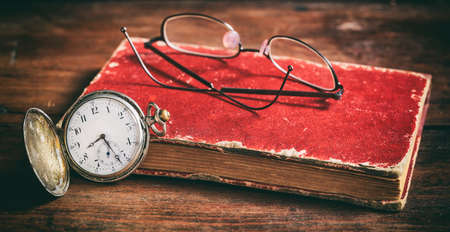 Pocket watch and eye glasses on a vintage bookの写真素材
