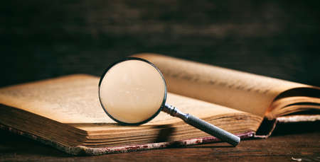 Vintage book and magnifying glass on wooden backgroundの写真素材