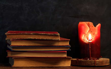 Vintage books stack and a candle on a dark backgroundの写真素材