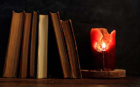 Vintage books and candle on wooden deskの写真素材
