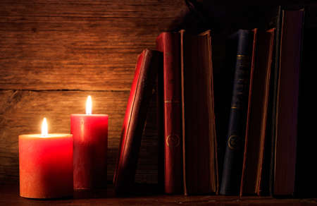 Vintage books and candles on a wooden deskの写真素材