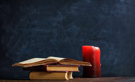 Vintage books and candle on blackboard background - copy spaceの写真素材